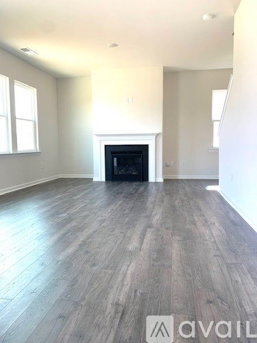 A spacious room with a fireplace and wood flooring.