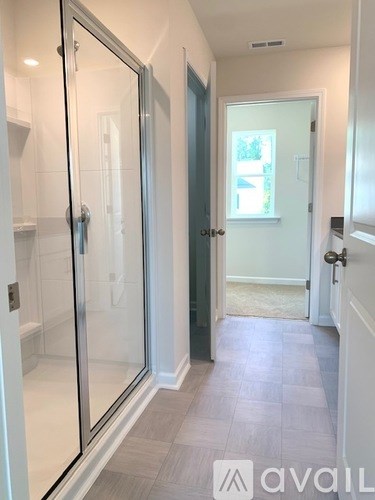 A hallway with a glass door and a white door.