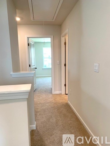 A hallway with a carpeted floor and white walls.