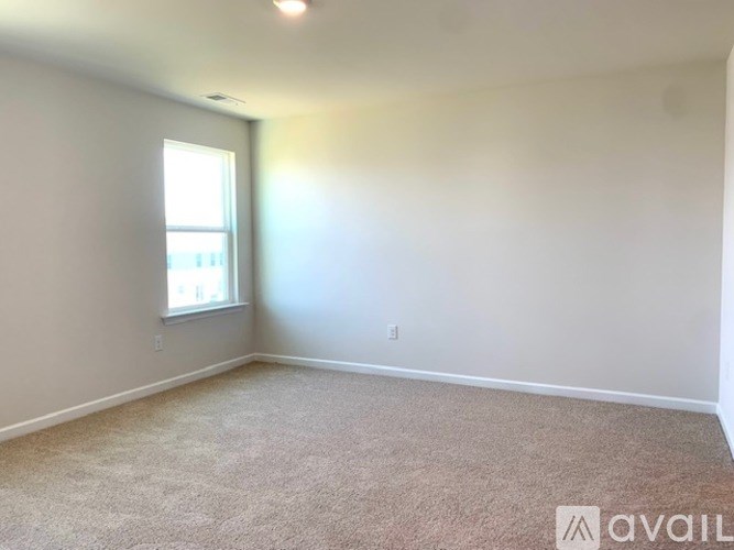 A room with a carpeted floor and a window letting in natural light.