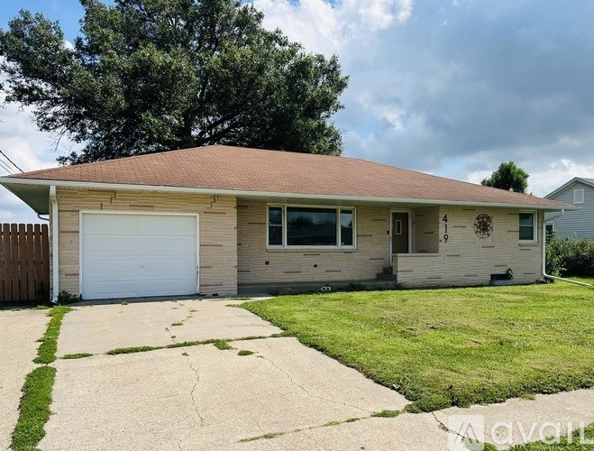 A two-car garage with a brown roof and a white door is situated in front of a house.