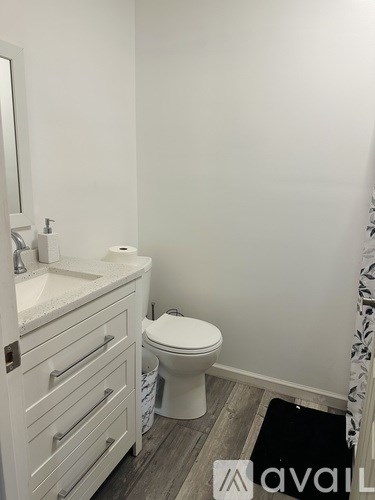 A bathroom with a toilet, sink, and mirror.