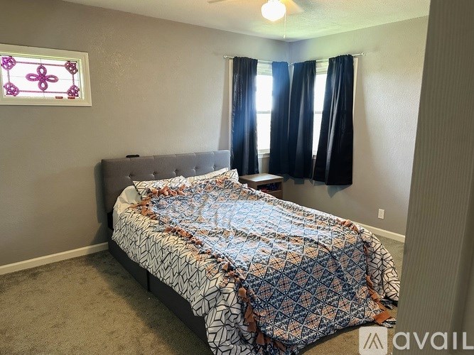 A bedroom with a bed covered in a patterned comforter.