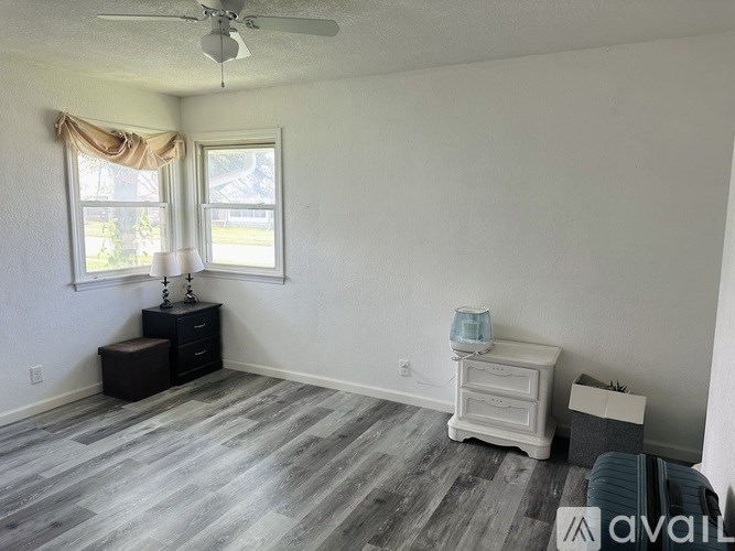 A room with a ceiling fan and two windows.