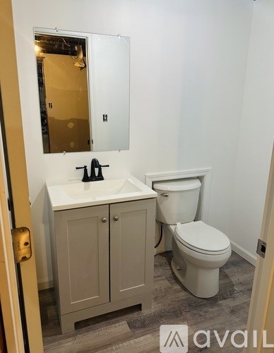 A bathroom with a toilet, sink and cabinet.