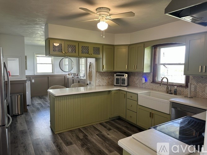 A kitchen with green cabinets and a white countertop.