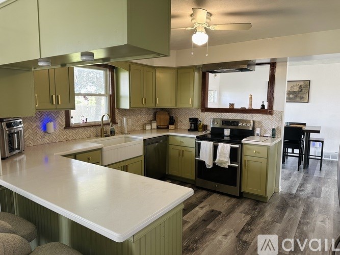 A kitchen with a white countertop and green cabinets.