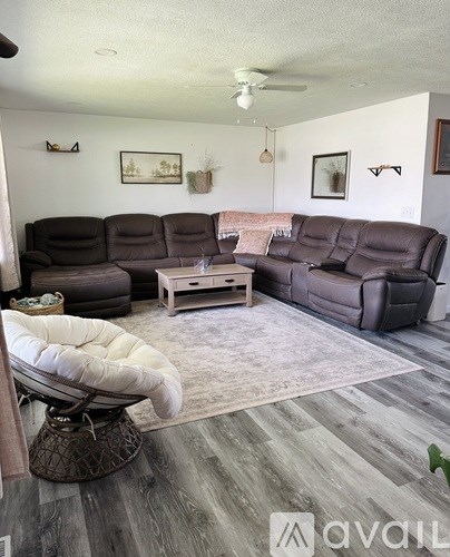 A living room with a grey sofa set and a white rocking chair.