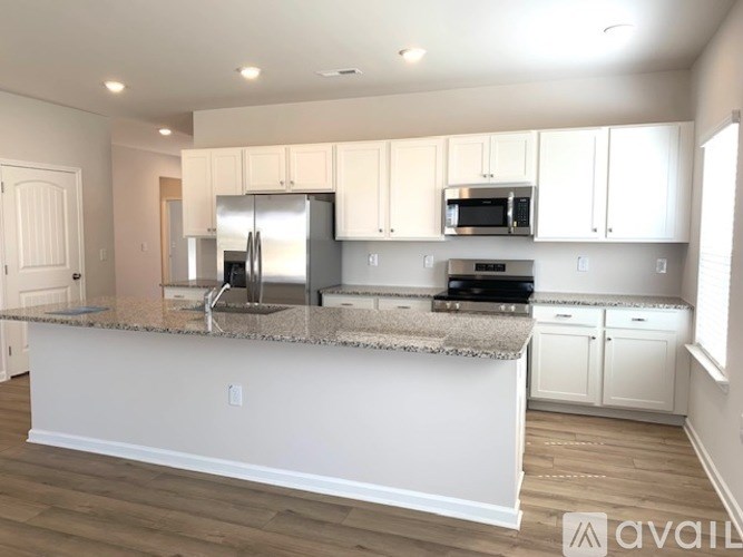 A kitchen with white cabinets and a granite countertop.