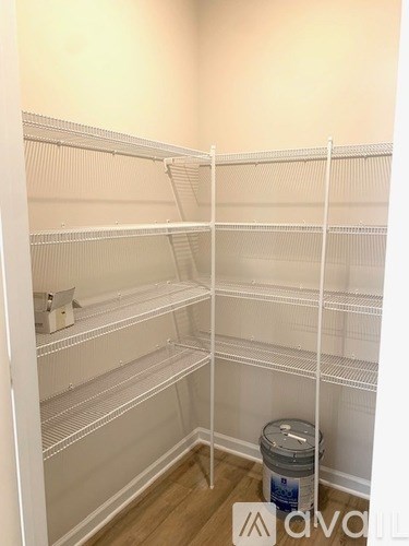 A white refrigerator with a white bucket on the floor.