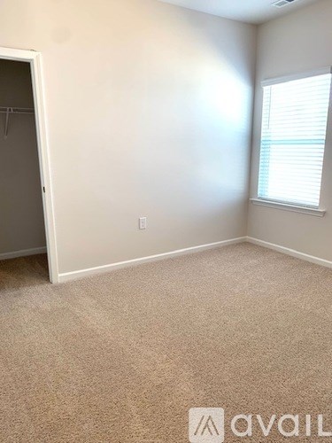 A room with a carpeted floor and a window with blinds.