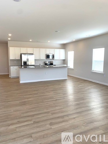 A spacious kitchen with wooden flooring and white cabinetry.