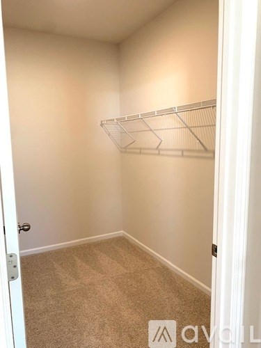 A white door is open to a room with a carpeted floor and a white shelf on the wall.