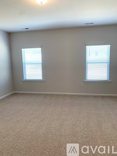 A room with two windows and carpeted floor.