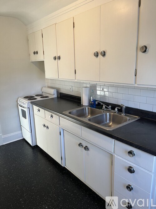 A kitchen with white cabinets and black countertops.