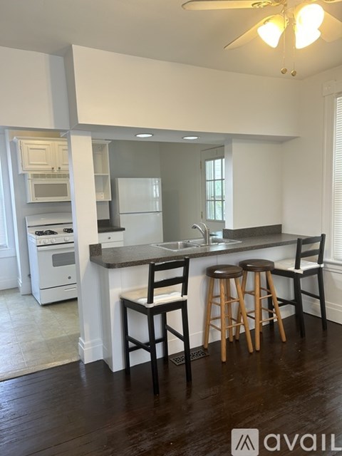 A kitchen with white appliances and wooden bar stools.
