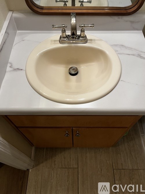 A bathroom sink with a marble counter top and a wooden cabinet below it.