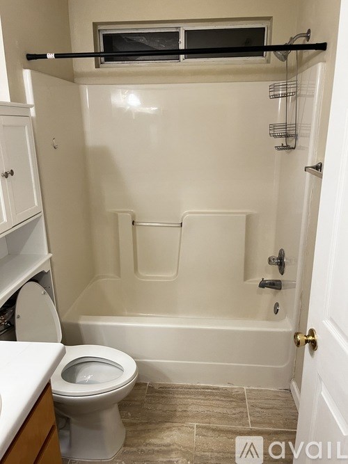 A white bathroom with a toilet, tub, and shelves.