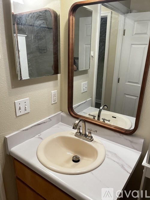 A bathroom sink with a marble counter top and a mirror above it.