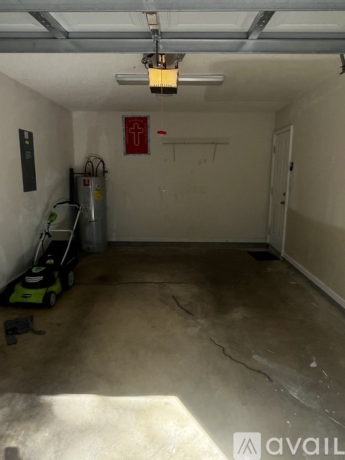 A garage with a red cross sign on the wall and a lawn mower on the floor.