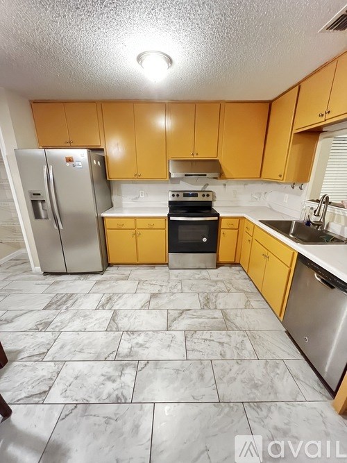 A kitchen with yellow cabinets and a marble floor.