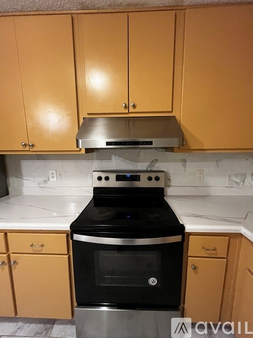 A kitchen with a black stove top oven and wooden cabinets.