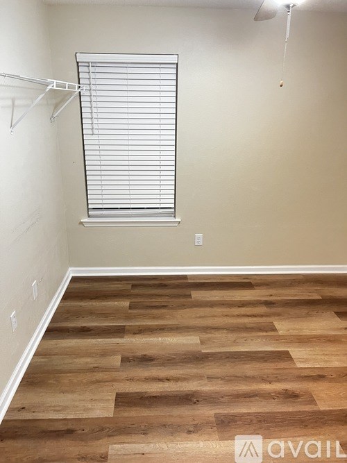A room with wooden flooring and a window with blinds.