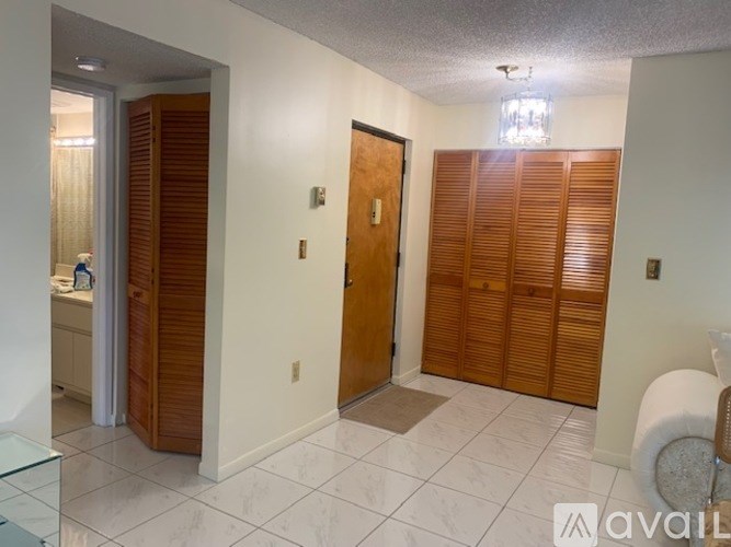 A hallway with a woman standing by a sink and two wooden doors.