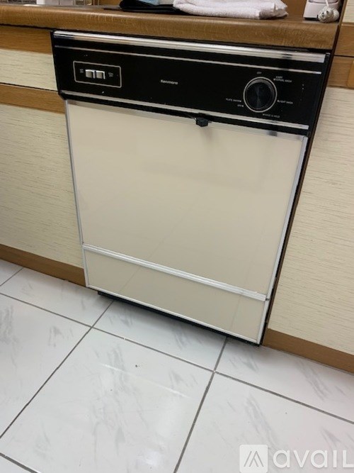 A white and black dishwasher is sitting on a tiled floor.