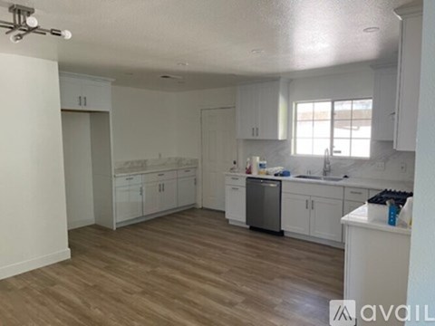 A kitchen with white cabinets and a wooden floor.