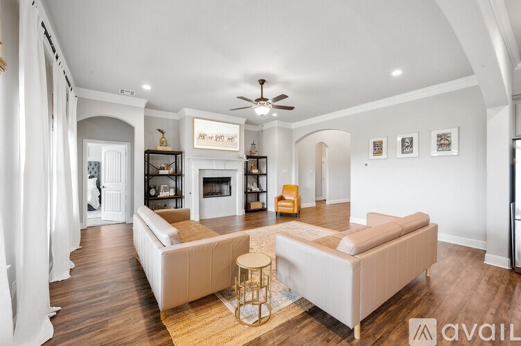 A spacious living room with a white sofa set and a fireplace.