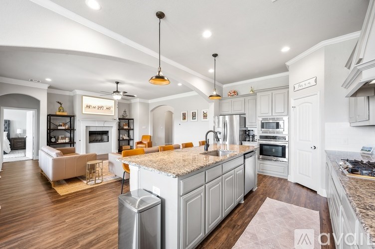 A modern kitchen with a central island and a living area with a fireplace.
