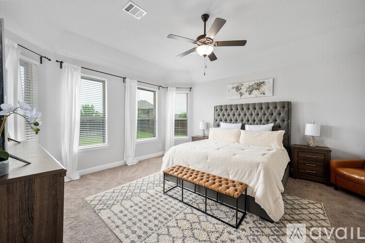 A bedroom with a large bed and a ceiling fan.