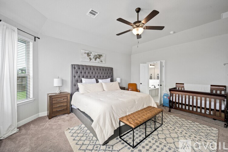 A bedroom with a large bed, a bench, and a ceiling fan.
