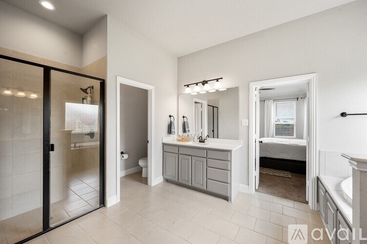 A bathroom with a glass door, a sink, a mirror, and a bathtub.