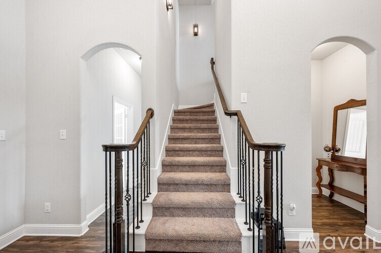 A staircase with a carpeted runner and black balusters.
