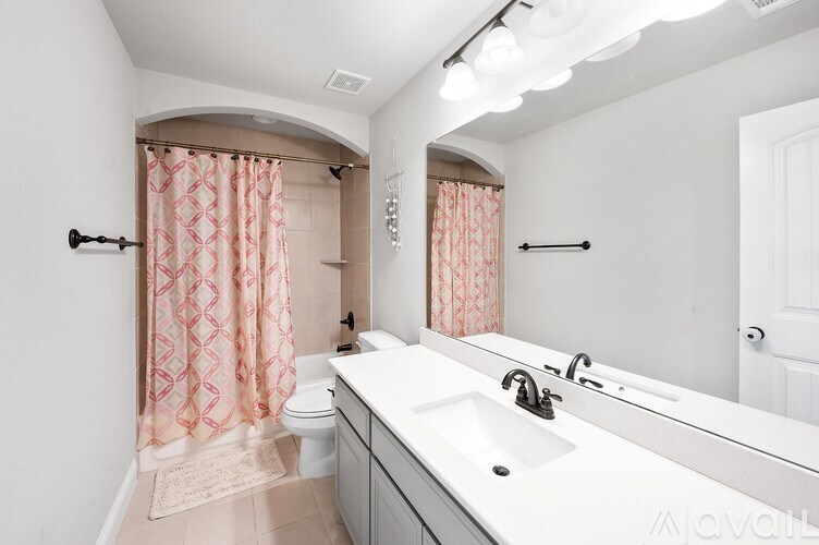 A bathroom with a sink, mirror, and shower curtain.