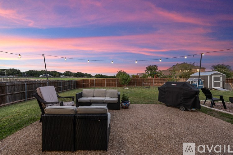 A backyard with a patio set and a covered grill area.