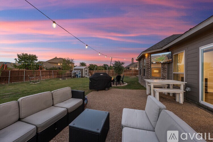 A backyard with a patio furniture set and string lights.