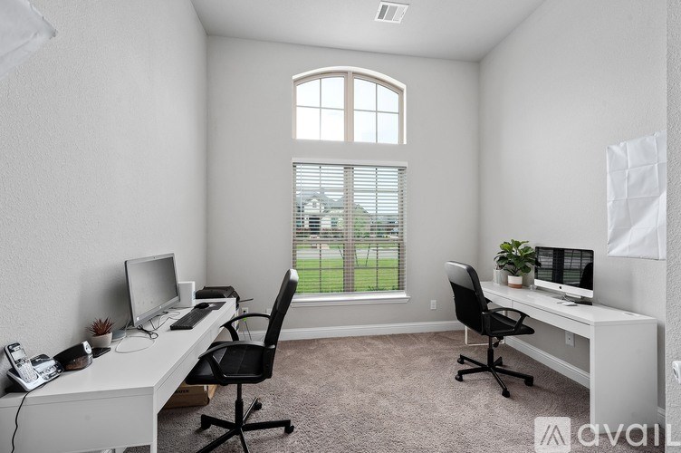 A white desk with a computer and a black chair in a room with a window.