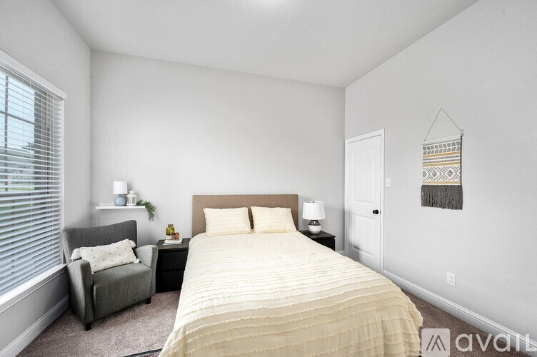 A bedroom with a bed, chair, and window.