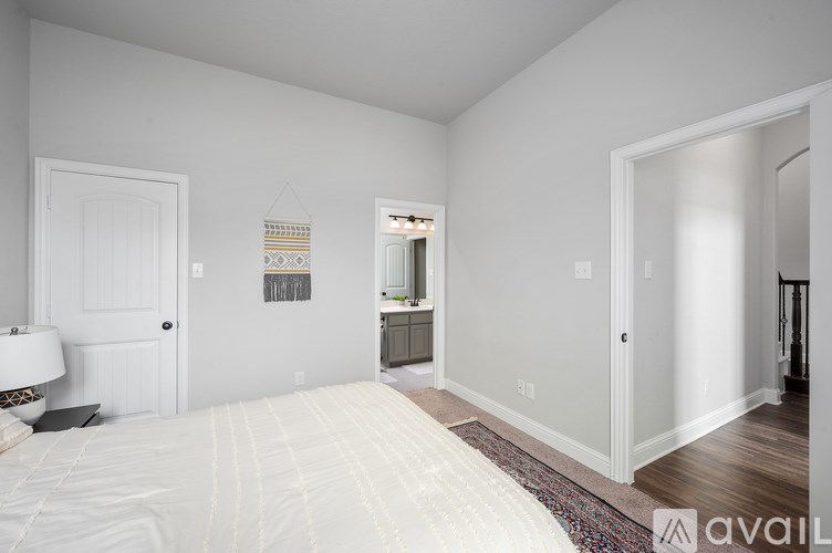 A bedroom with a large bed and a rug on the floor.
