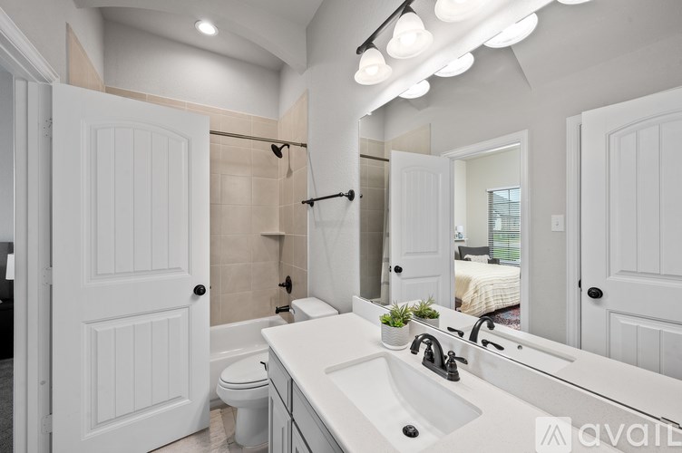 A bathroom with a white sink and a large mirror.