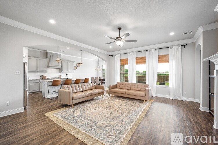 A spacious living room with a beige sofa and a rug in the center.