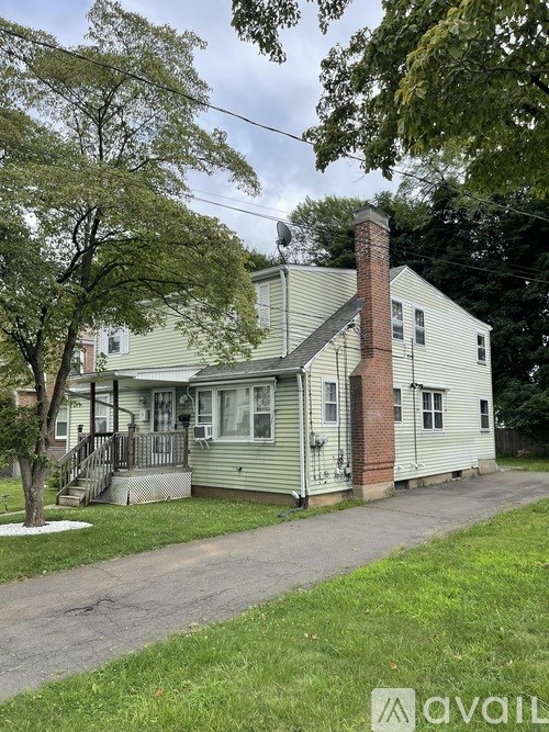 A house with a green siding and a red brick chimney.