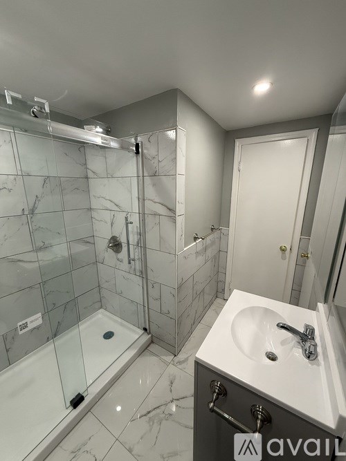 A bathroom with a marble tile shower and a white sink.