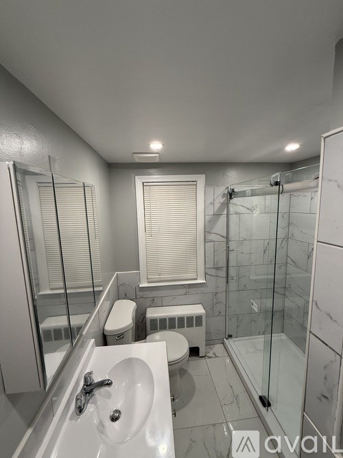 A bathroom with a white sink, toilet, and a glass shower stall.