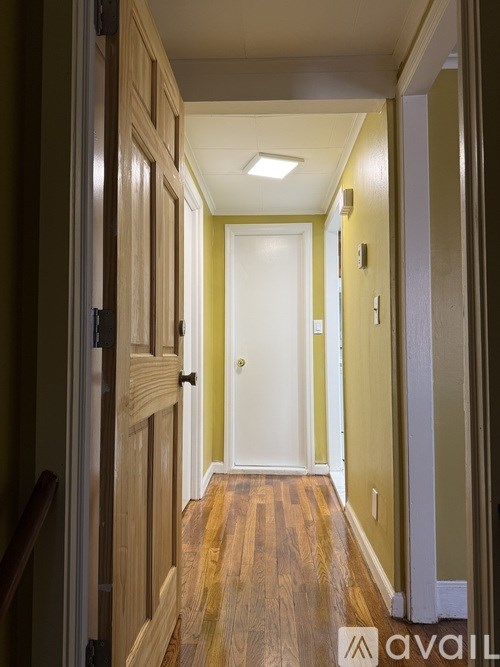 A hallway with a wooden floor and white door.