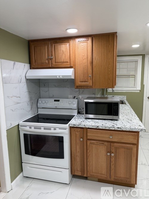 A kitchen with a white oven and microwave on a granite countertop.