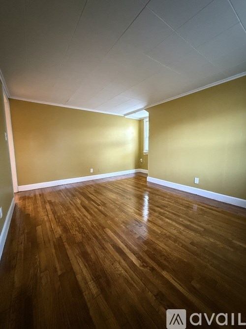 A room with wooden flooring and a door on the right side.